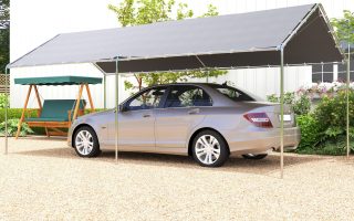 Gray carport shelter covering parked car and swing seat in driveway.
