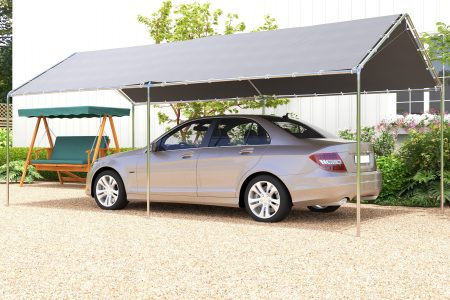 Gray carport shelter covering parked car and swing seat in driveway.