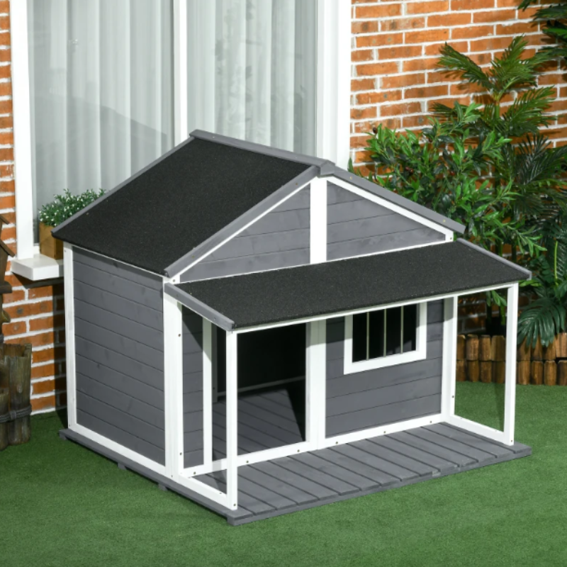 Large outdoor dog house with porch roof placed in a garden near a brick home.
